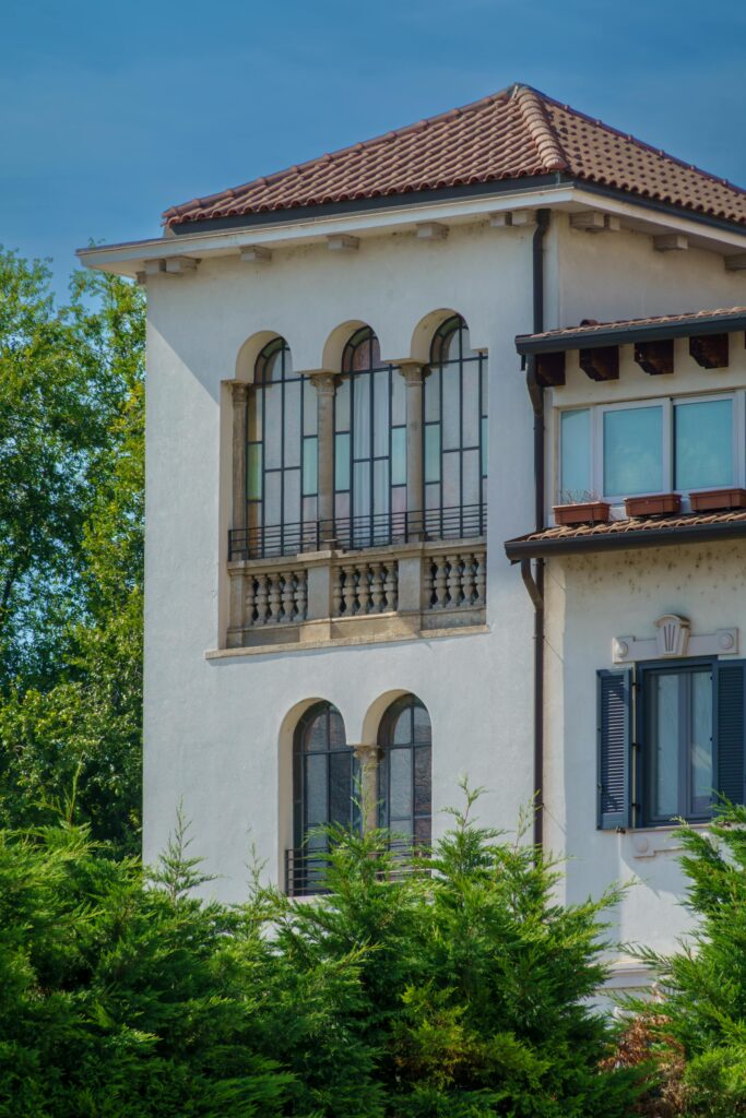 Elegant Mediterranean villa with terracotta roof and arched windows in a sunny setting.