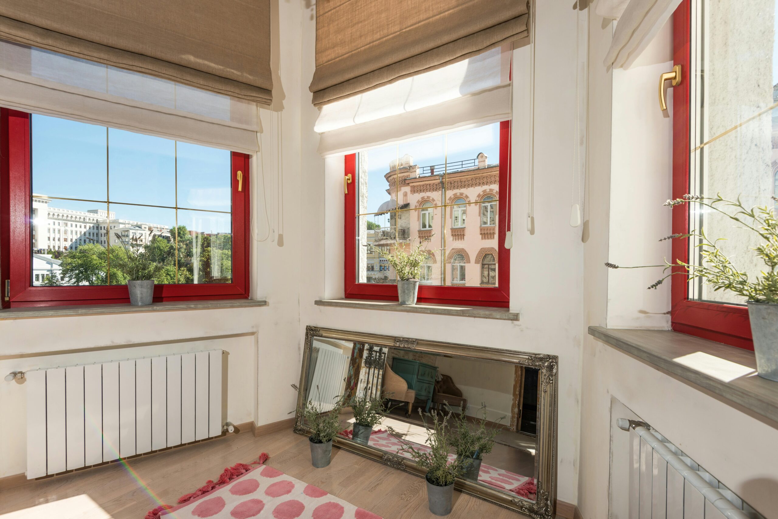 Bright apartment interior showcasing red windows overlooking the city.
